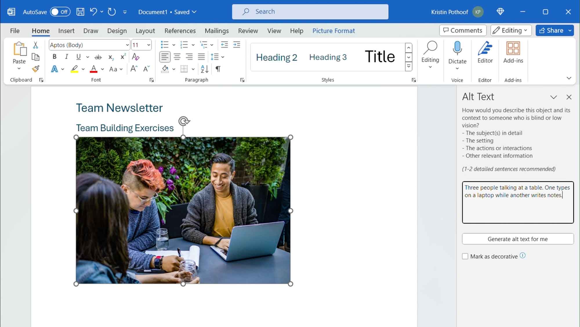 Screenshot of Microsoft Word with the Alt Text pane open for the selected image, and the following alt text description: Three people talking at a table. One types on a laptop while another writes notes.